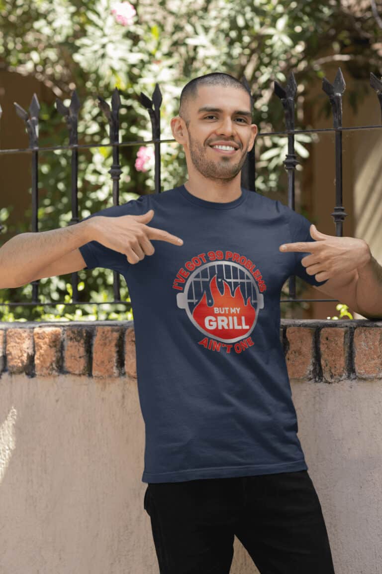 Lifestyle mockup of the witty, grilling-inspired 99 Problems, But My Grill Ain't One print by Relateeble on a dark grey colored unisex/men's short sleeve tee